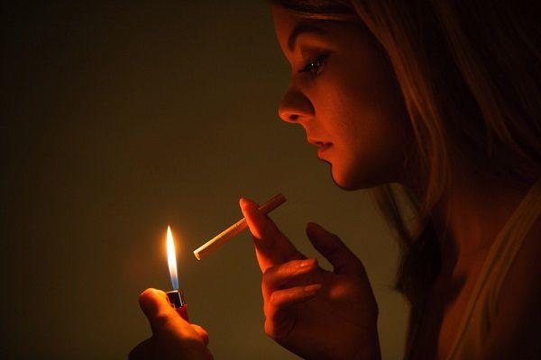 薄暗い部屋でタバコに火を点ける女性