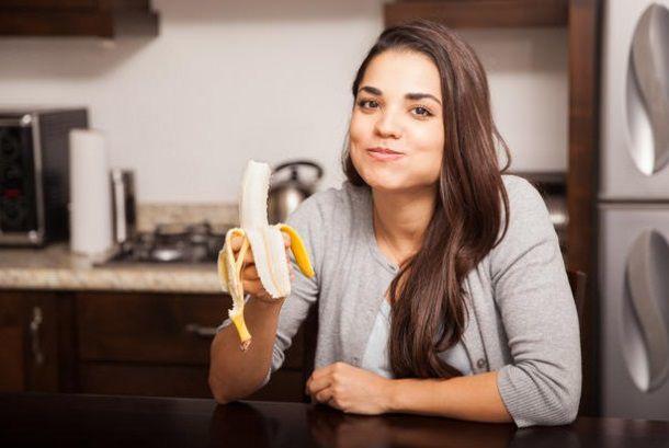 ダイニングでバナナを食べる女性